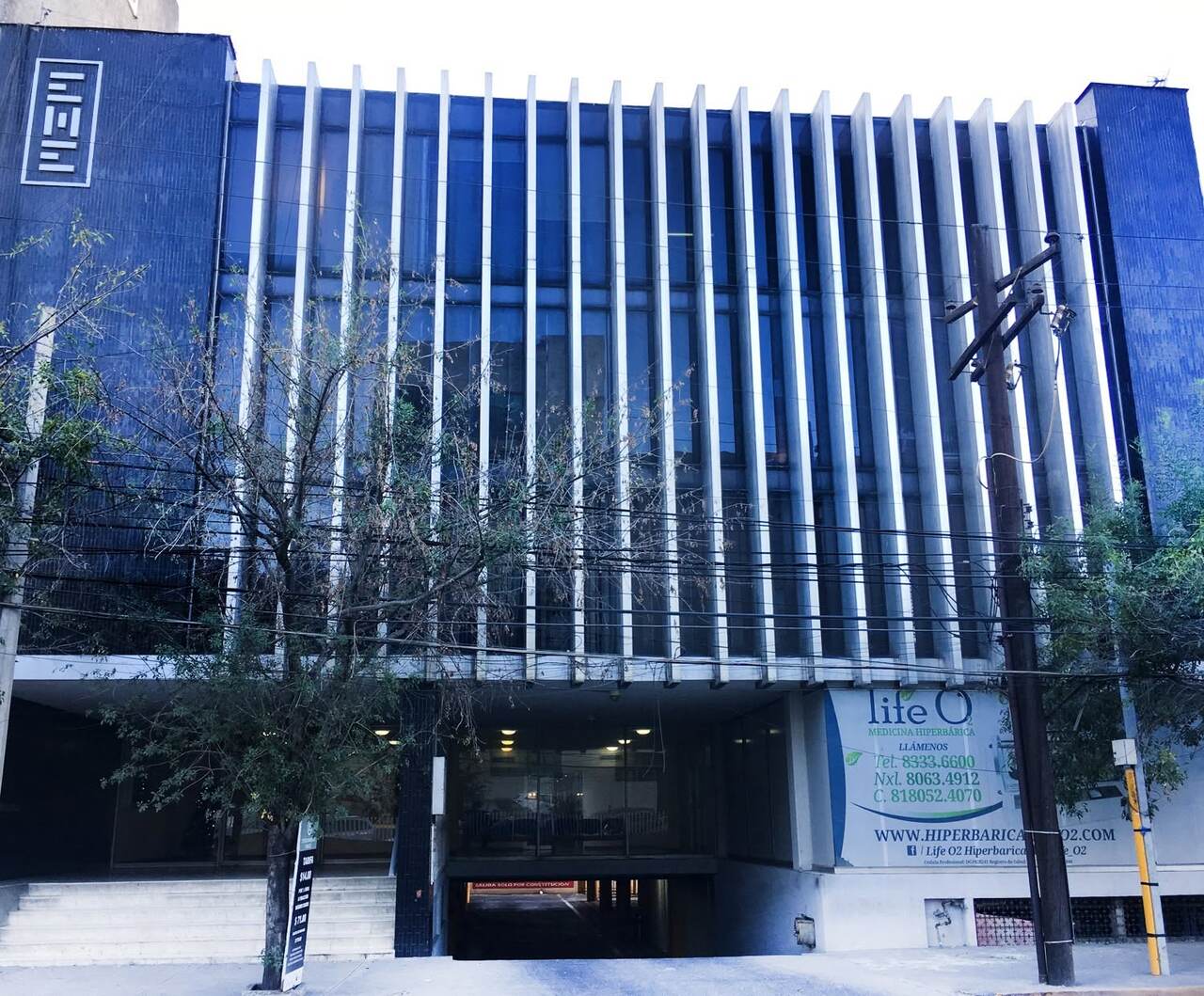 Fachada del Edificio Médico de Especialistas en Hidalgo 2532: vidrio azul detrás de lamas blancas verticales y el letrero EME en la torre de azulejo